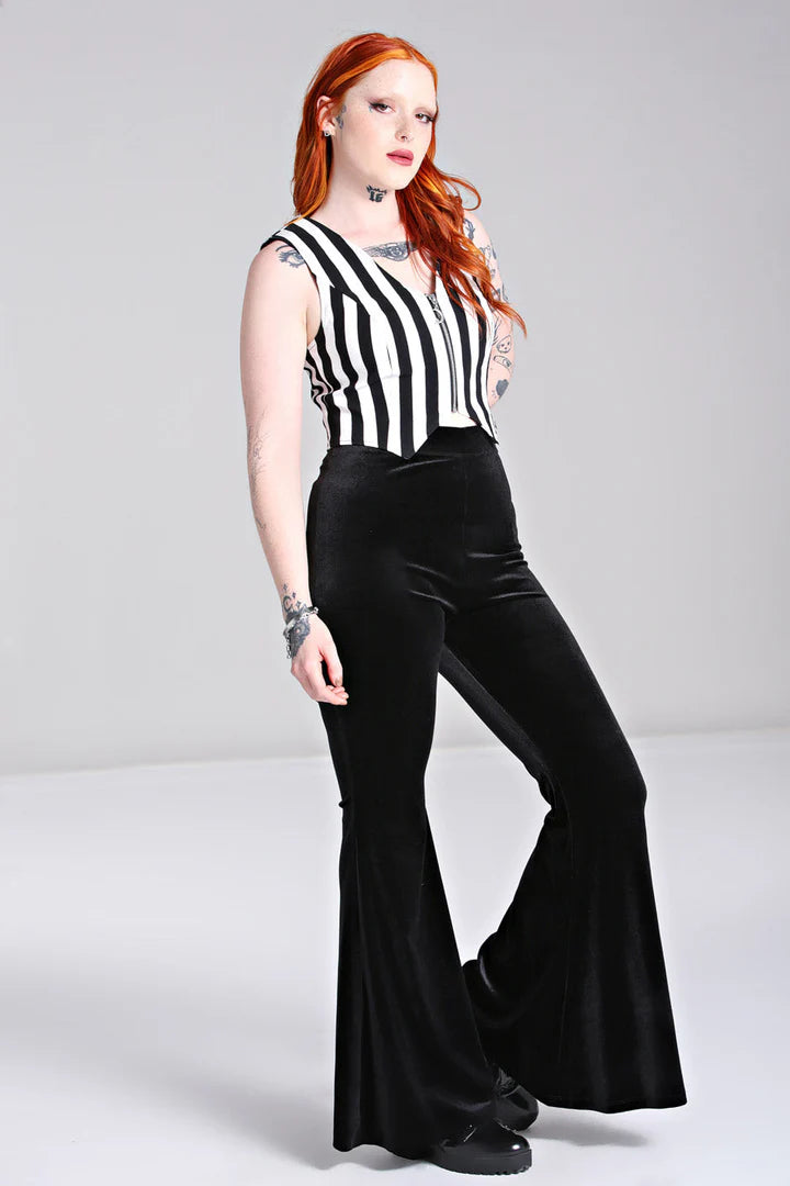 Person wearing a black and white striped sleeveless top with black bell-bottom pants on a gray background